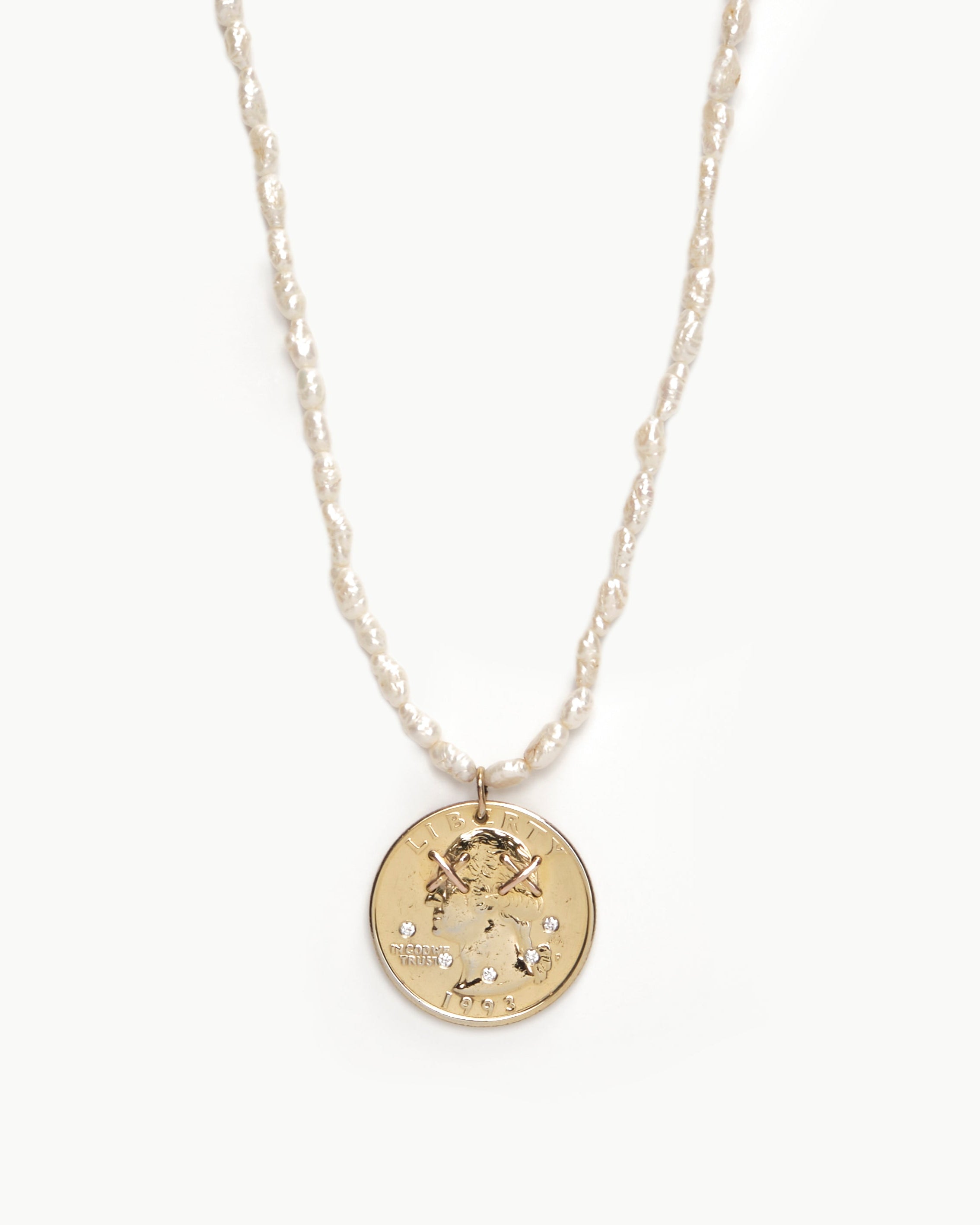 Upcycled gold plated quarter necklace on pearl stand, close up view. 
