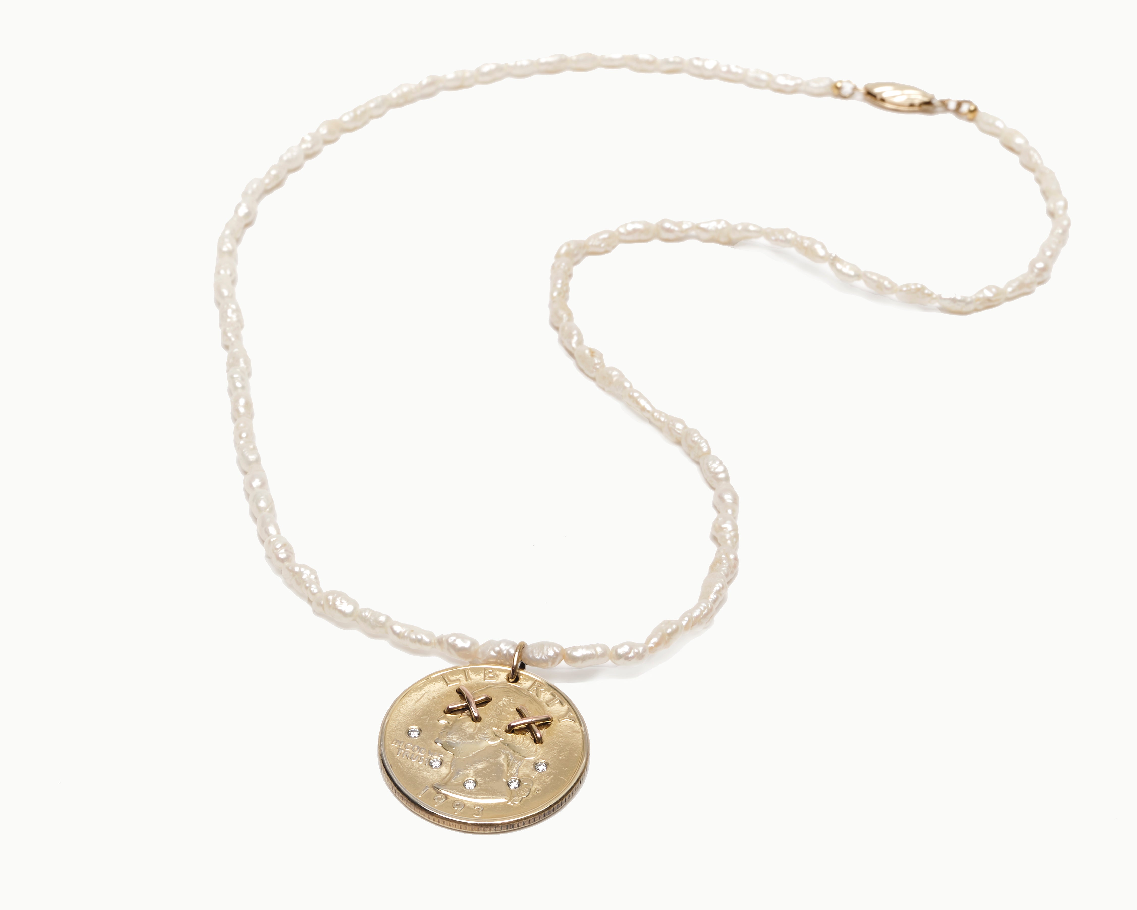 Upcycled gold plated quarter necklace on pearl stand, whole necklace view. 