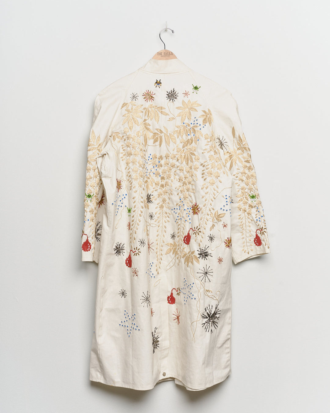 Long reworked white coat with embroidered motifs, back view. 