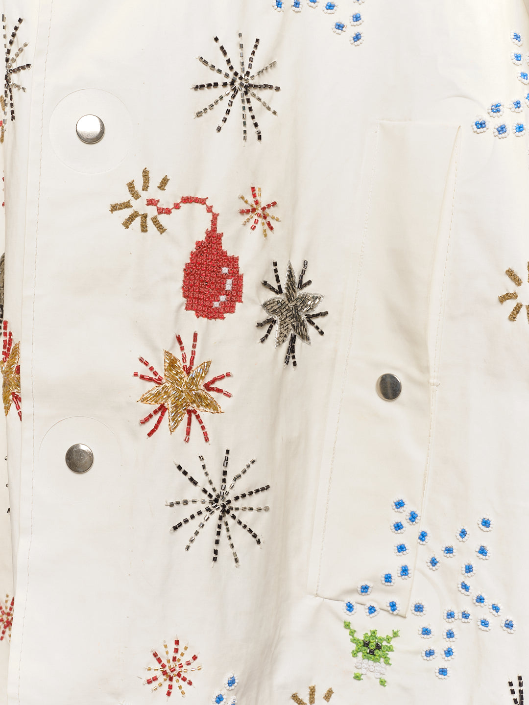 Long reworked white coat with embroidered motifs, close up of embroidery. 