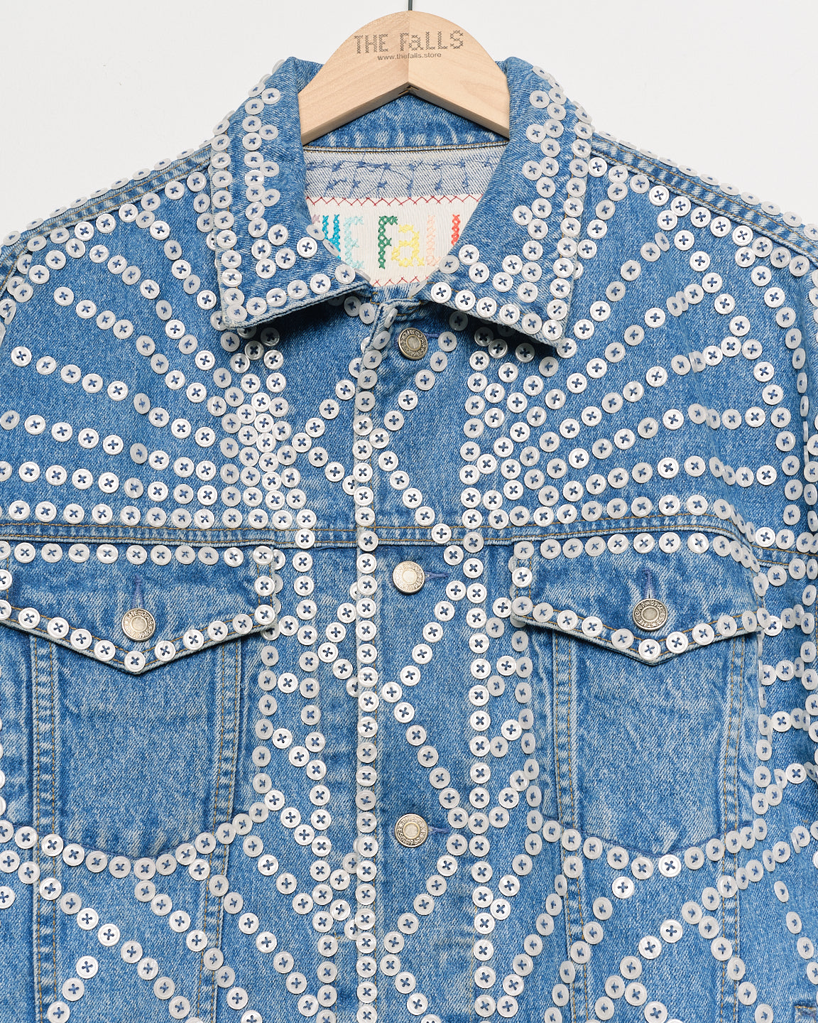 Upcycled denim jacket with pearly buttons, closeup view.