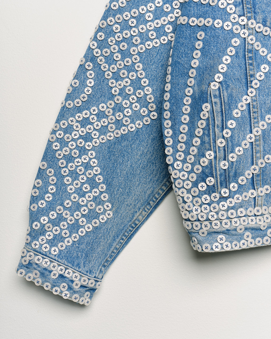 Upcycled denim jacket with pearly buttons, sleeve close up view.