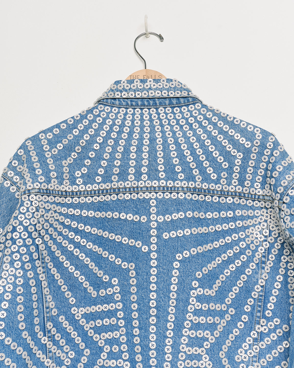 Upcycled denim jacket with pearly buttons, back close up view.