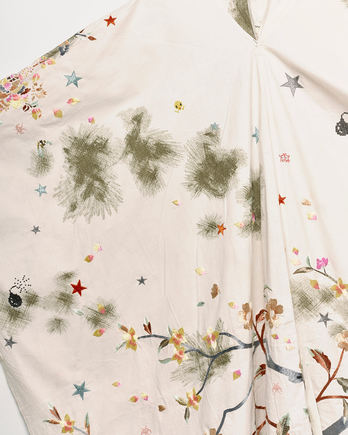 Upcycled floral snow camo hand embroidered poncho, close up embroidery view. 
