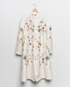 Long reworked white coat with embroidered motifs, front view. 