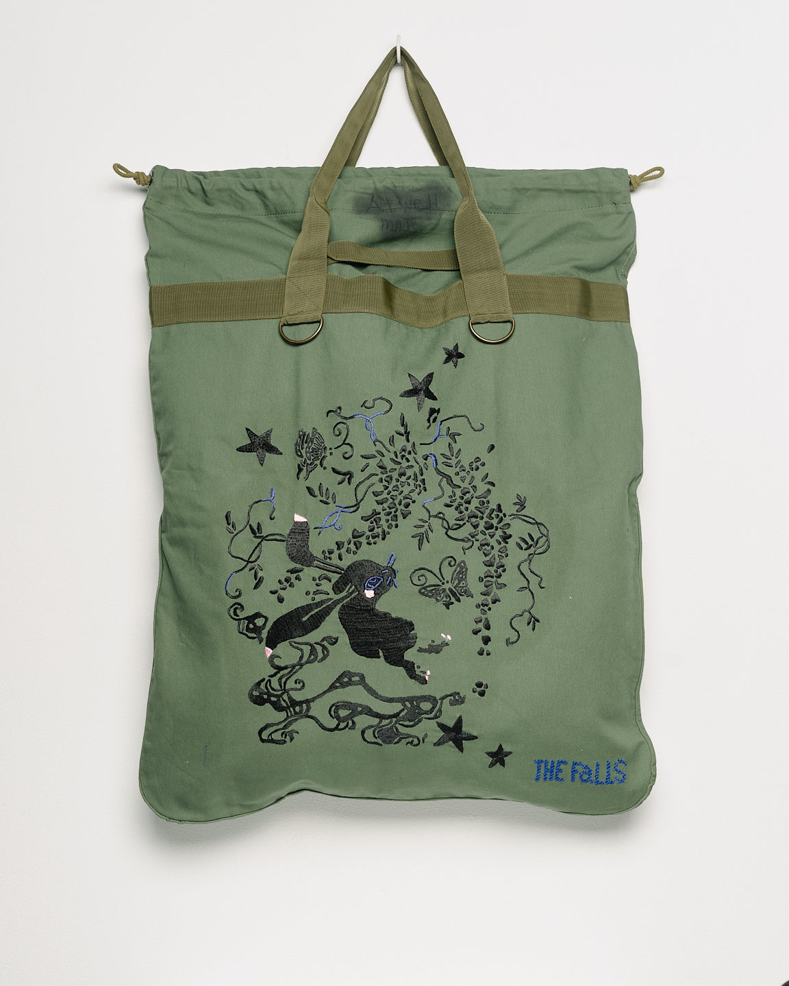 Vintage army surplus laundry tote with embroidered motifs, front view. 