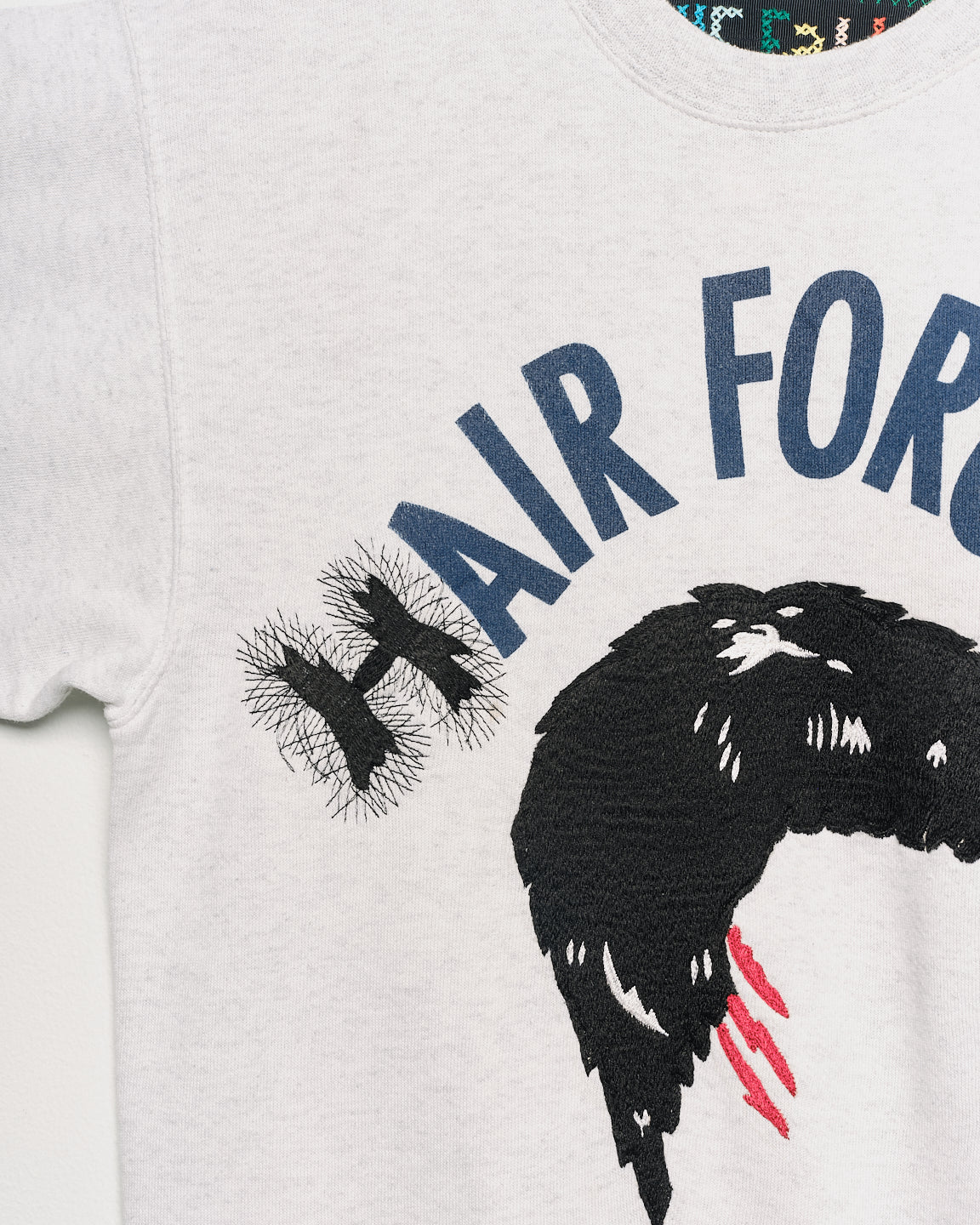 Upcycled sweatshirt with embroidery saying “hair force”, close up view. 