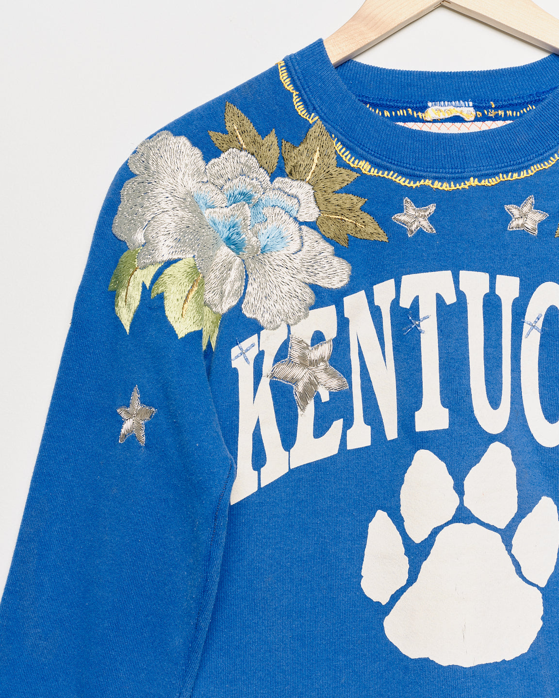 Upcycled sweatshirt with floral embroidery, close up view. 