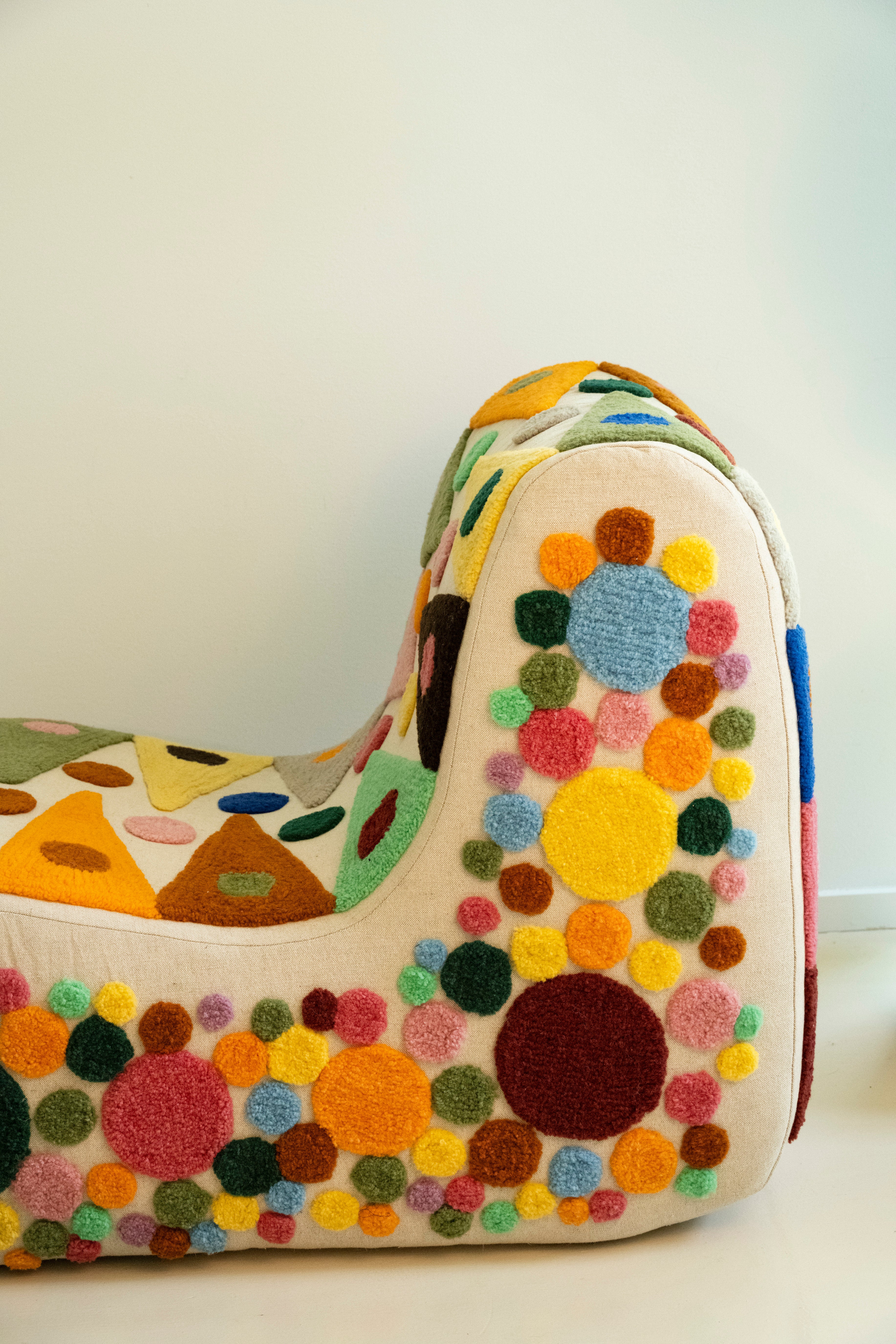 An upcycled tufted, sectional sofa with geometric wool triangles and diamonds pattern, side view.