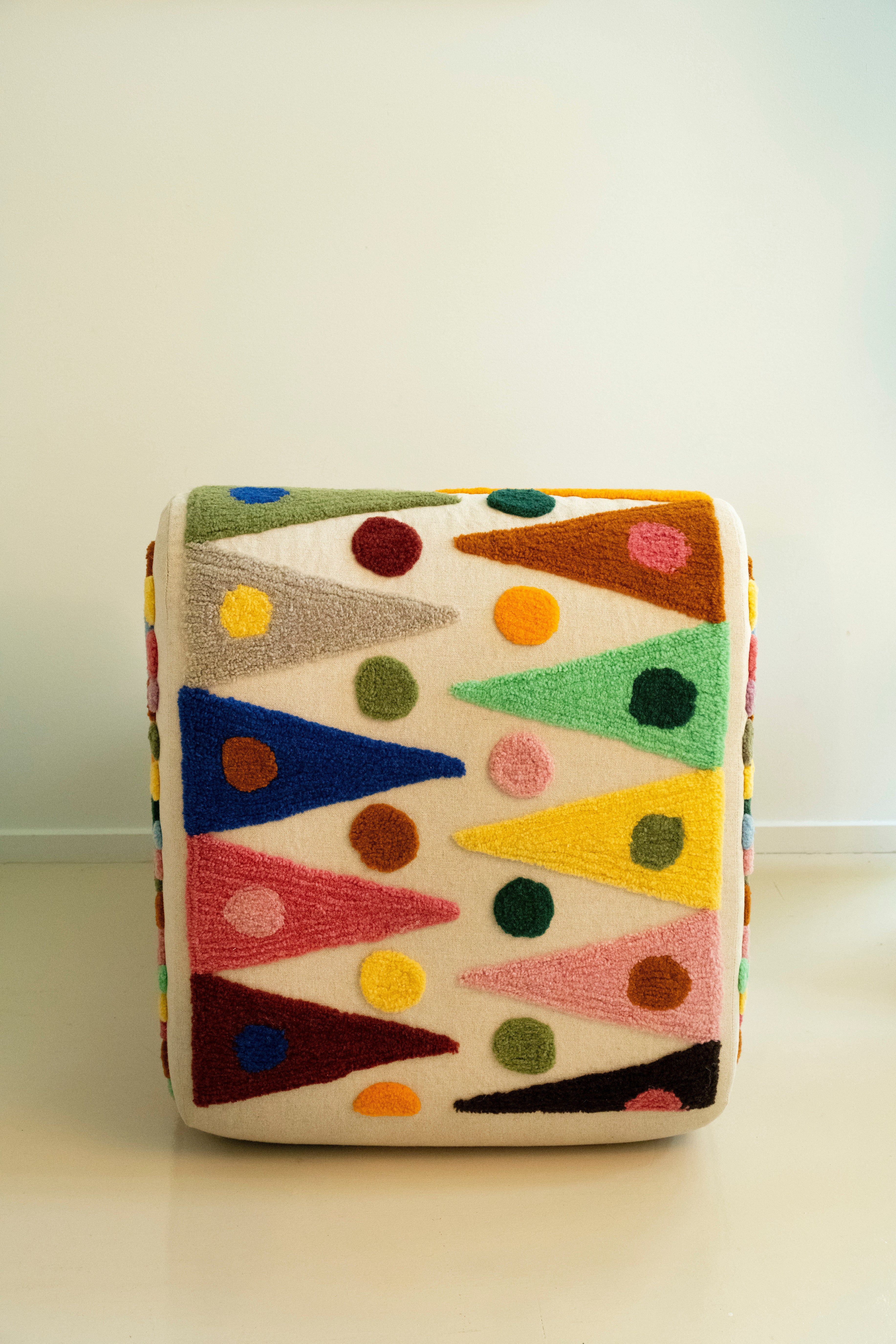 An upcycled tufted, sectional sofa with geometric wool triangles and diamonds pattern, back view.