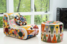 An upcycled tufted, sectional sofa with geometric wool triangles and diamonds pattern, in room with pouff. 