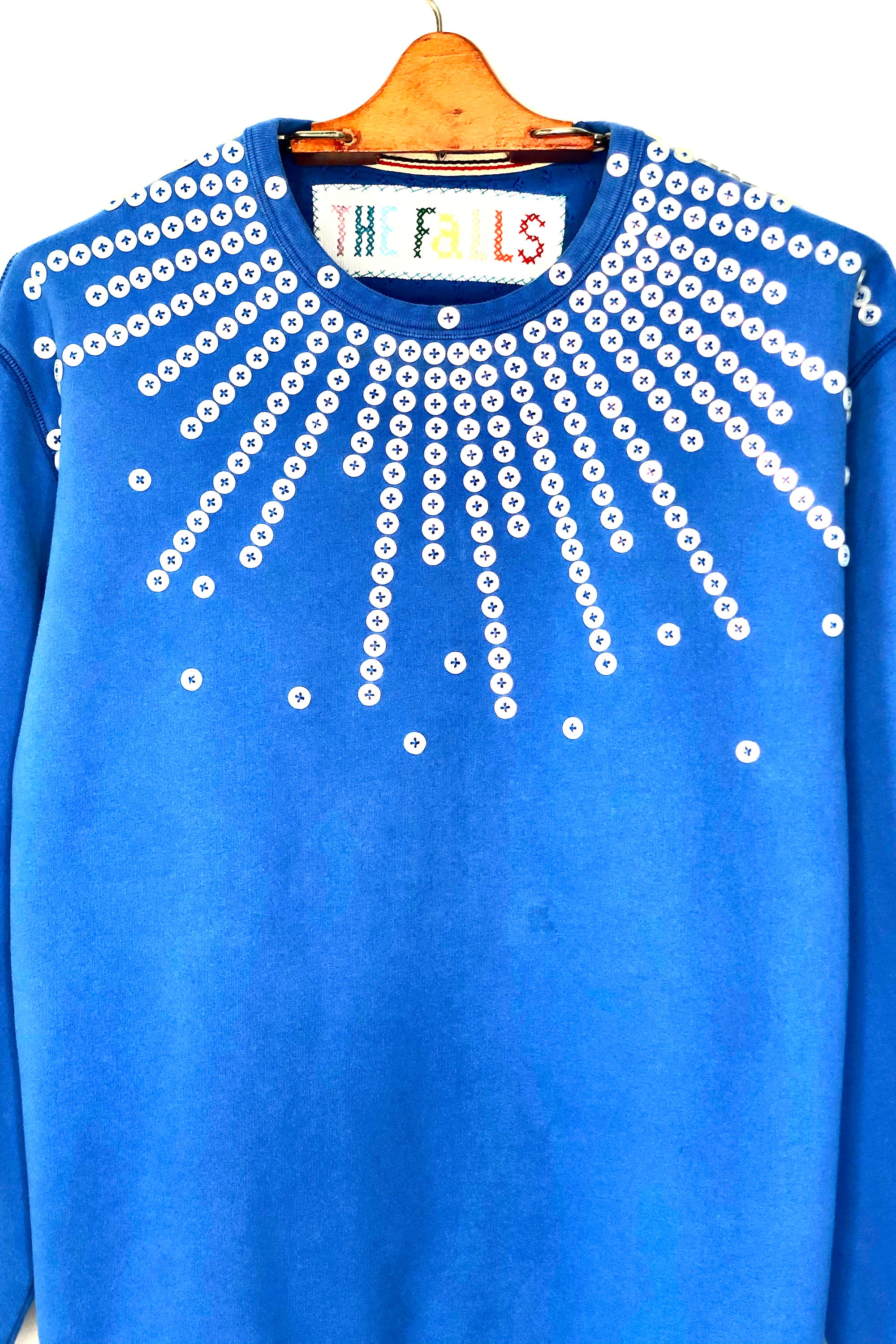 Upcycled sweatshirt with pearl button embellishments, close up view