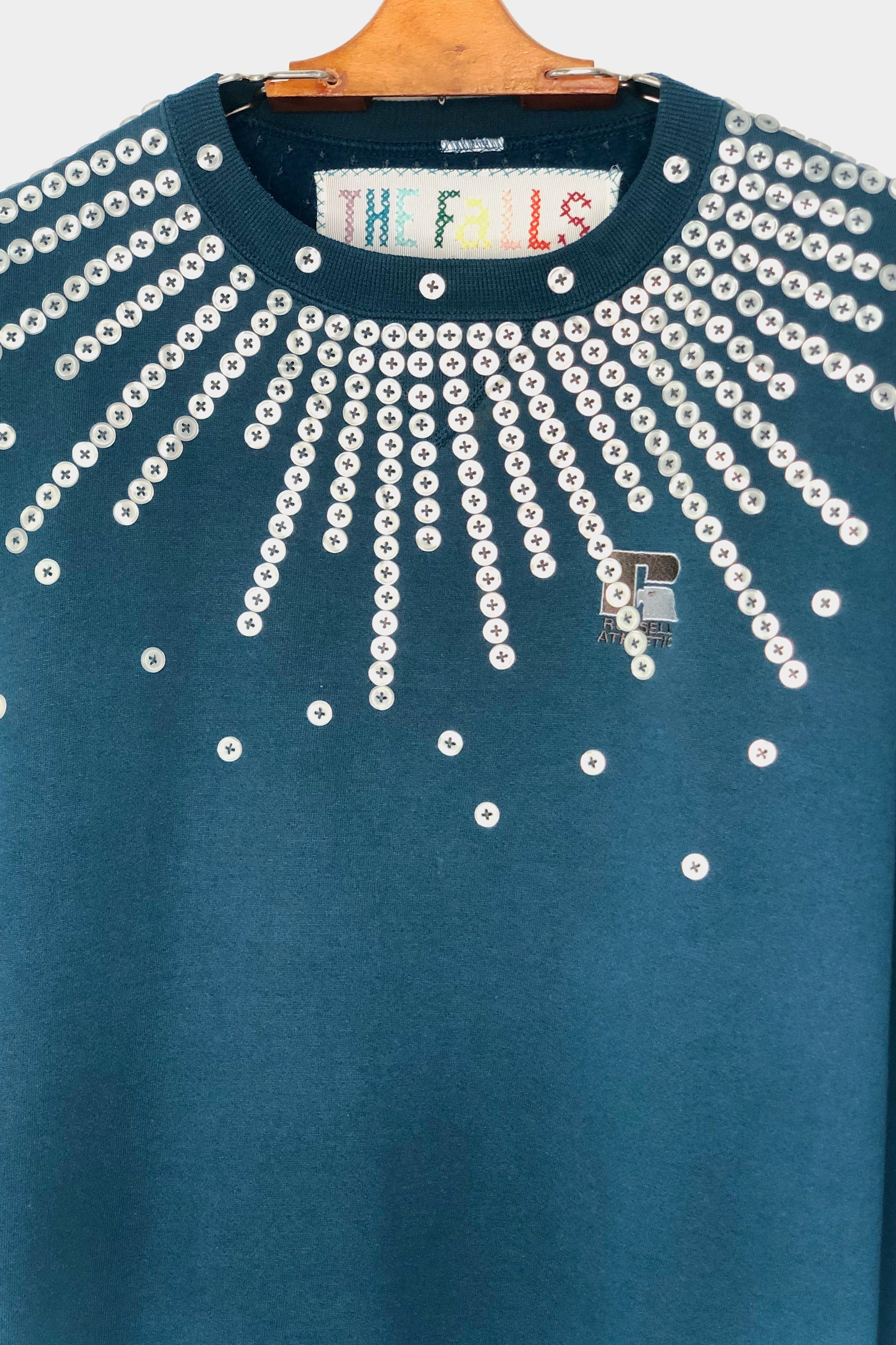 Upcycled sweatshirt with pearl button embellishments, close up view
