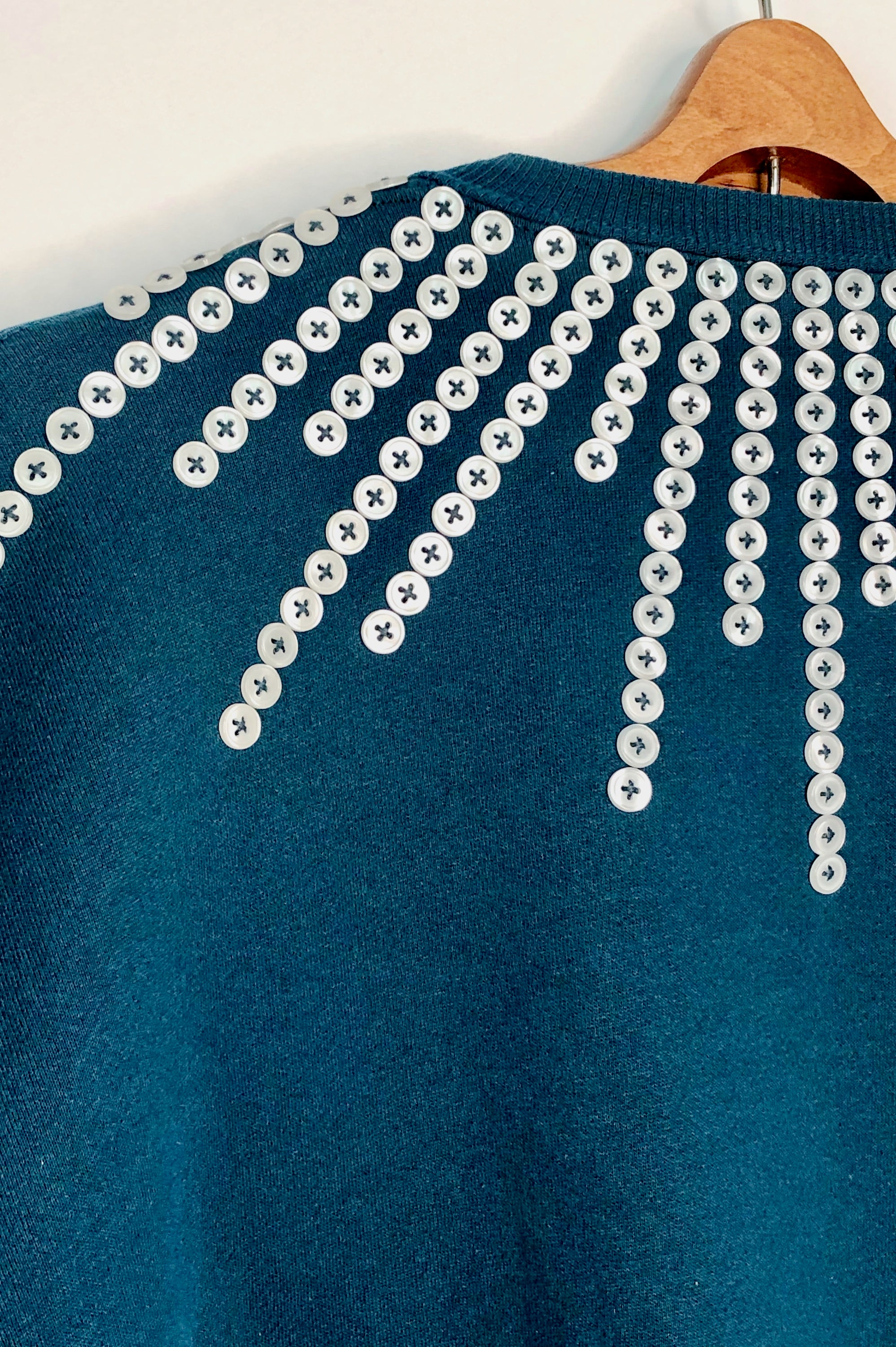 Upcycled sweatshirt with pearl button embellishments, close up view