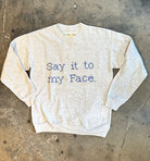 Upcycled sweatshirt with embroidery saying  “Say it to my face”, front view. 