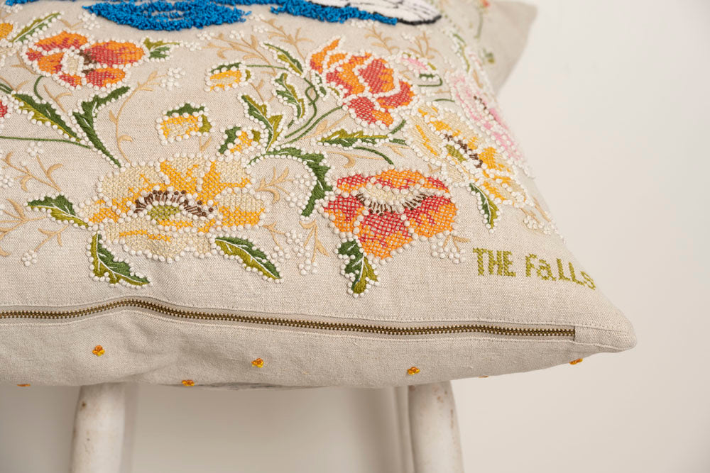 Pillow with embroidery and tufting embellishments, close up view 