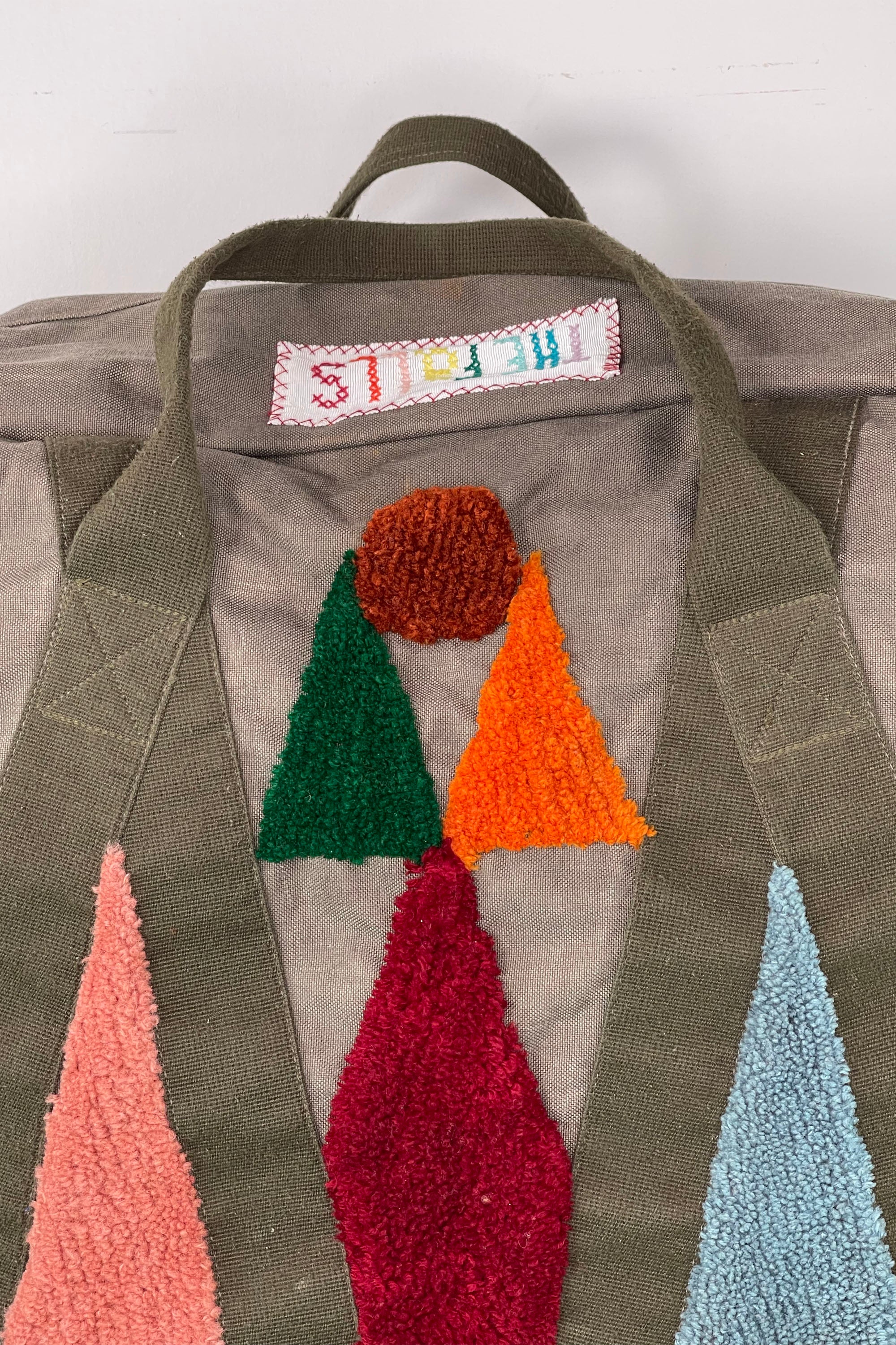 Upcycled aviator bag with tufted embellishments, close up view 