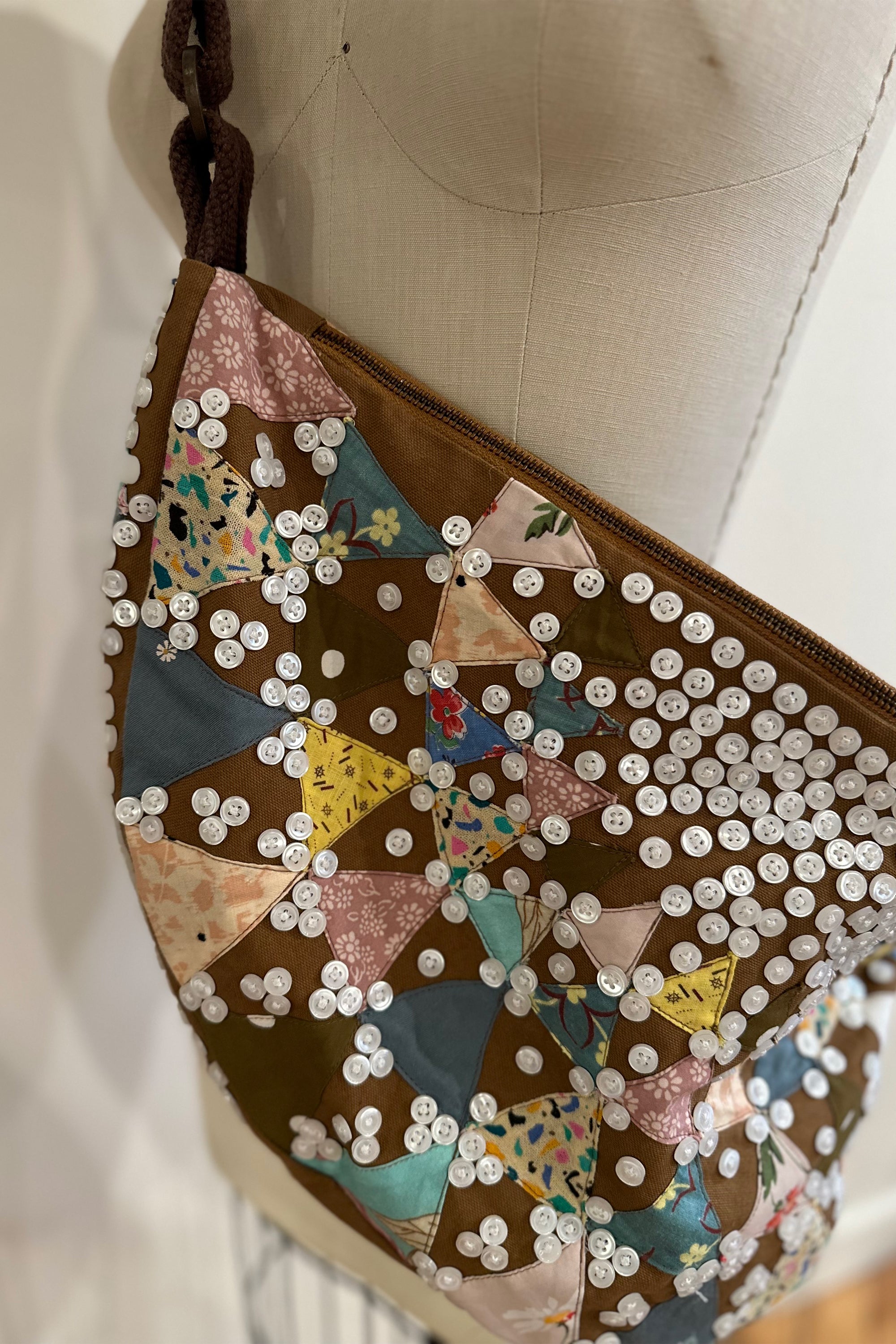 Sling bag with embroidered and button embellishments, close up view