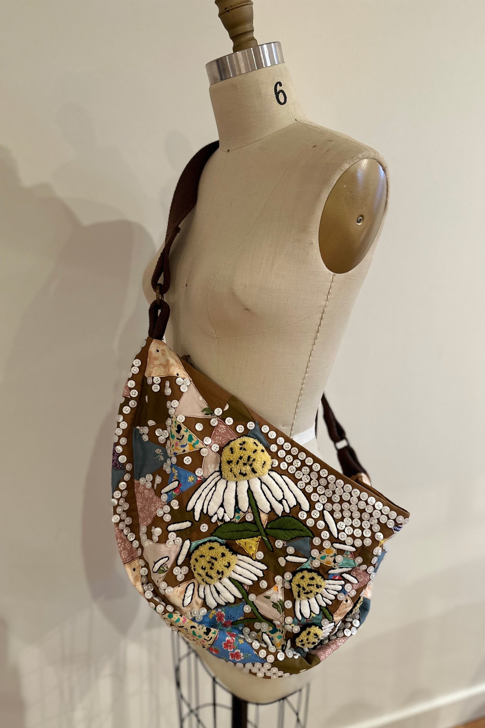 Sling bag with embroidered and button embellishments, front view