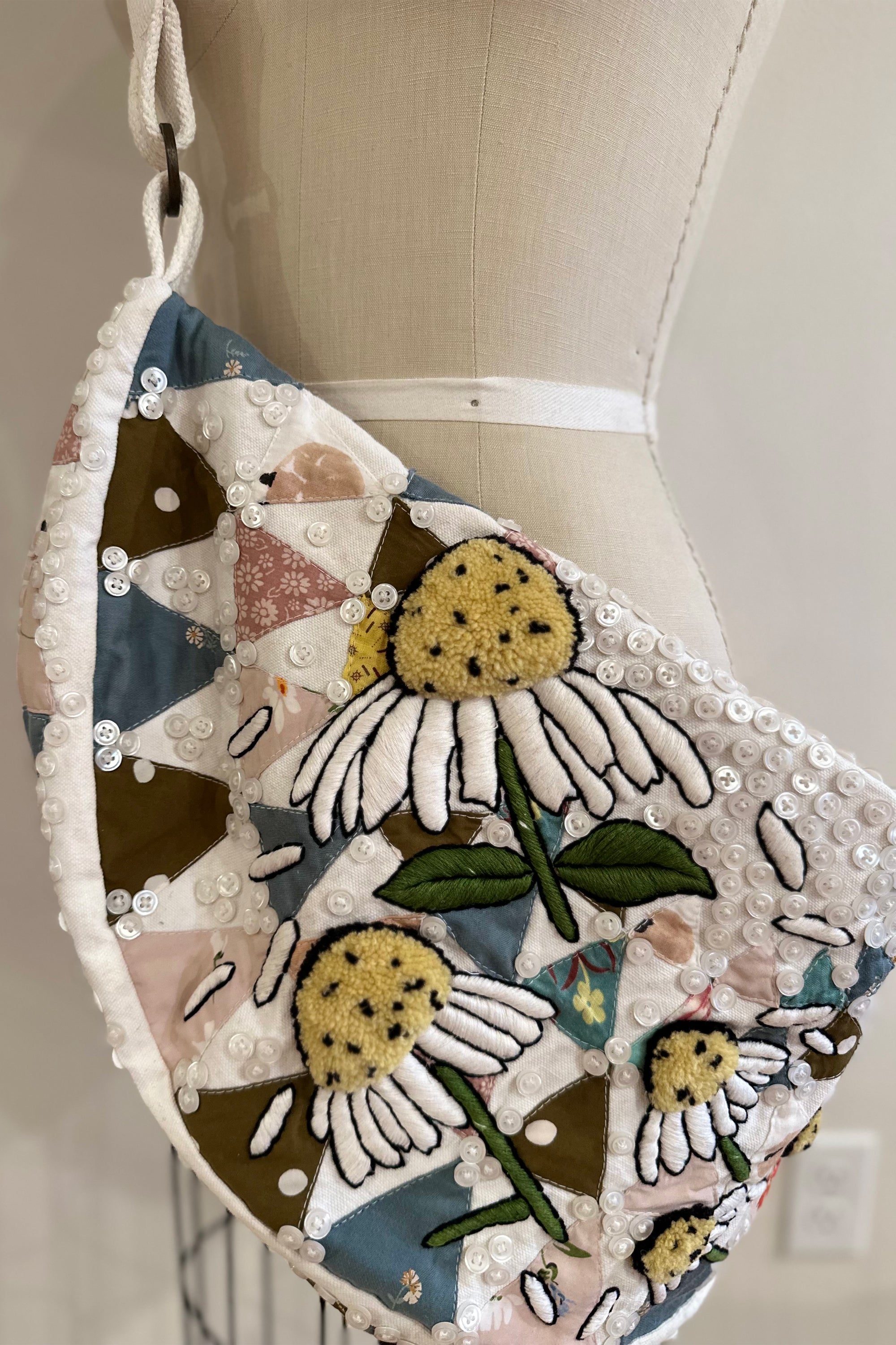 Sling bag with embroidered and button embellishments, close up view