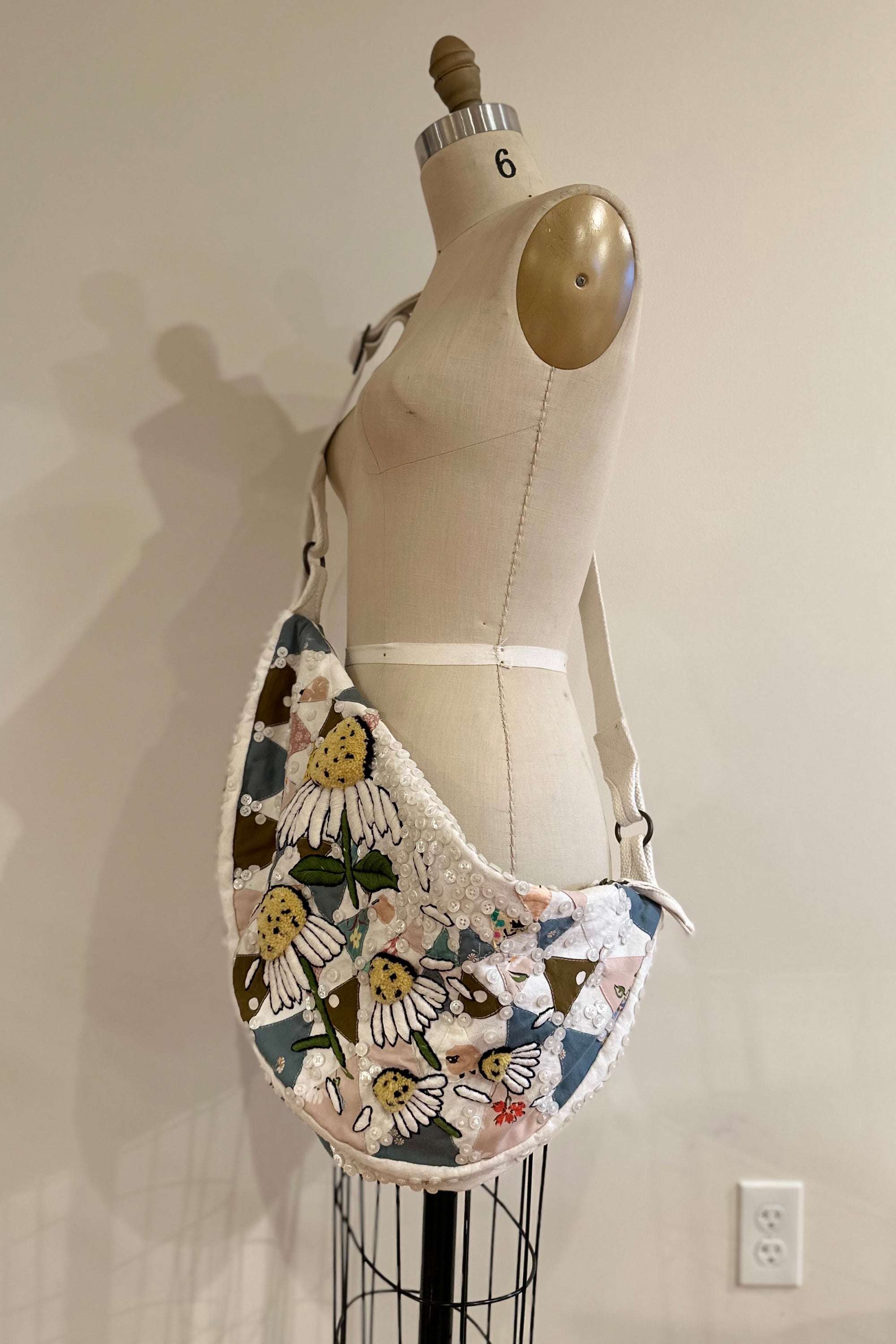 Sling bag with embroidered and button embellishments, front view