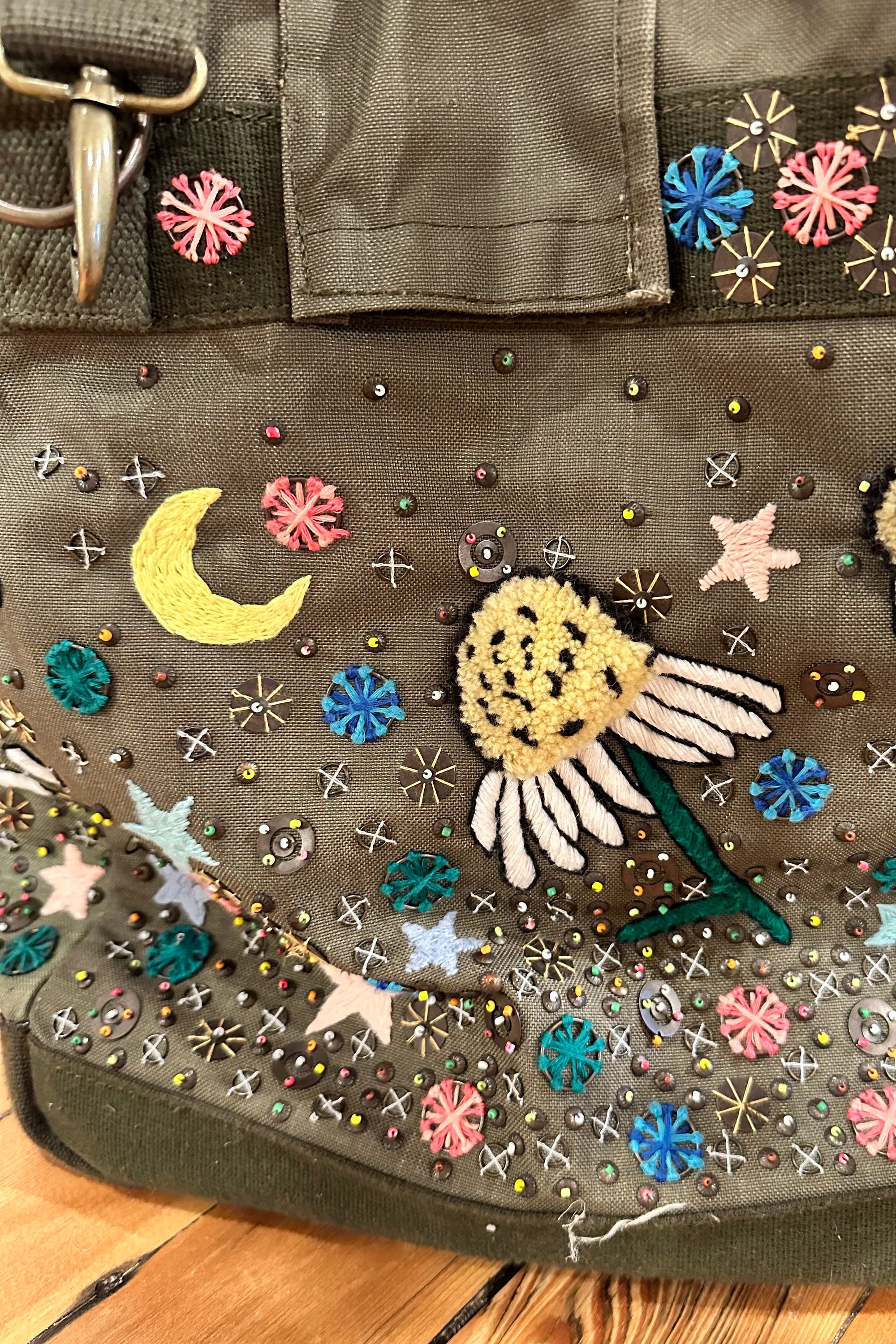 Upcycled aviator bag with embroidered embellishments, close up view 