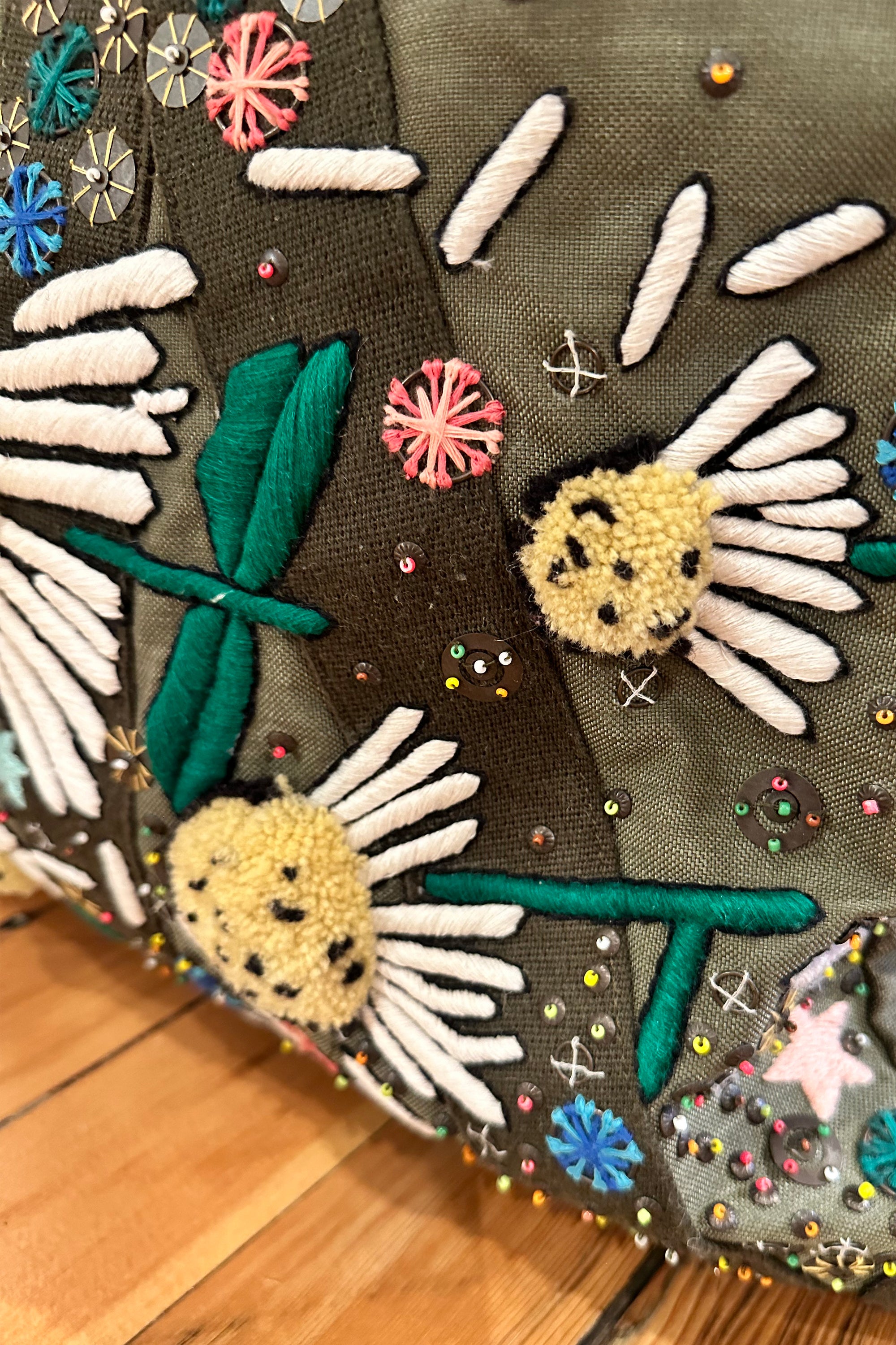 Upcycled aviator bag with embroidered embellishments, close up view 